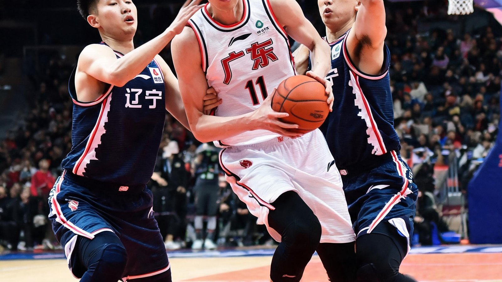 广东宏远队球员周琦在篮下强攻，辽宁队两人包夹防守